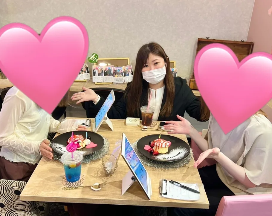 店内でスタッフを挟み、パンケーキとタブレットを前に座る来店客 2 名