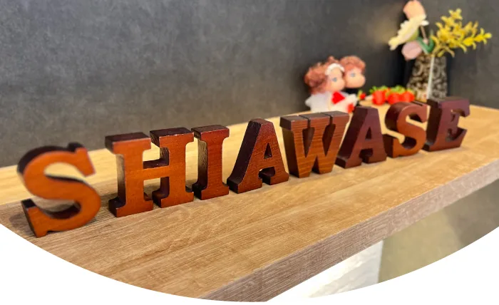棚に並べた木製の SHIAWASE の文字と、奥のカップル人形と花