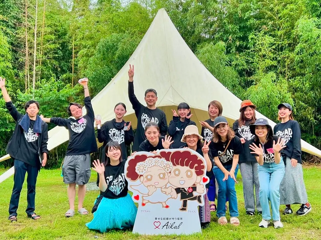 テントの前でアイクルのキャラクターパネルを囲むスタッフの集合写真