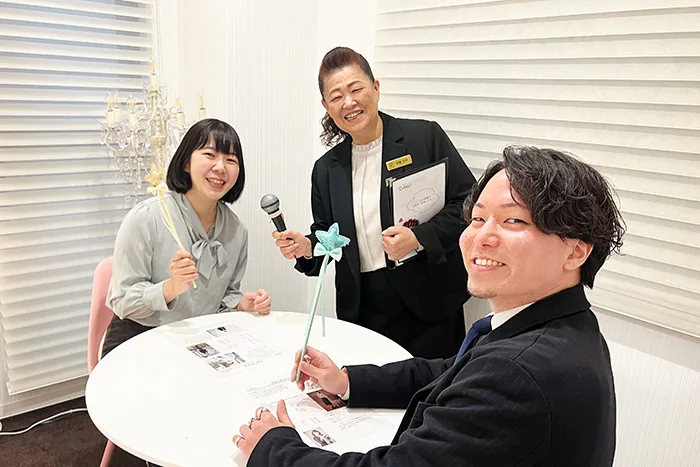 個室のテーブルで、スタッフを挟んで向かい合う男女の会員