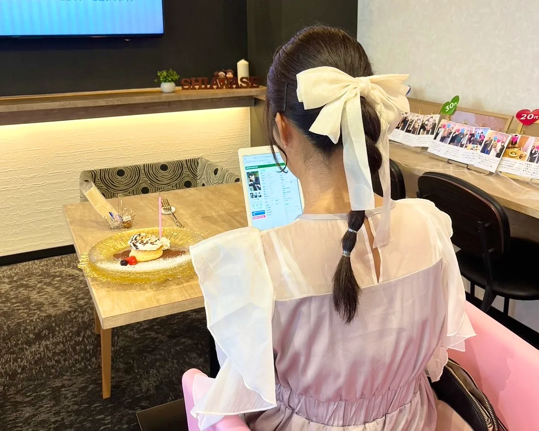 店内の席で婚活タブレットのプロフィールを見ている女性のお客様の写真